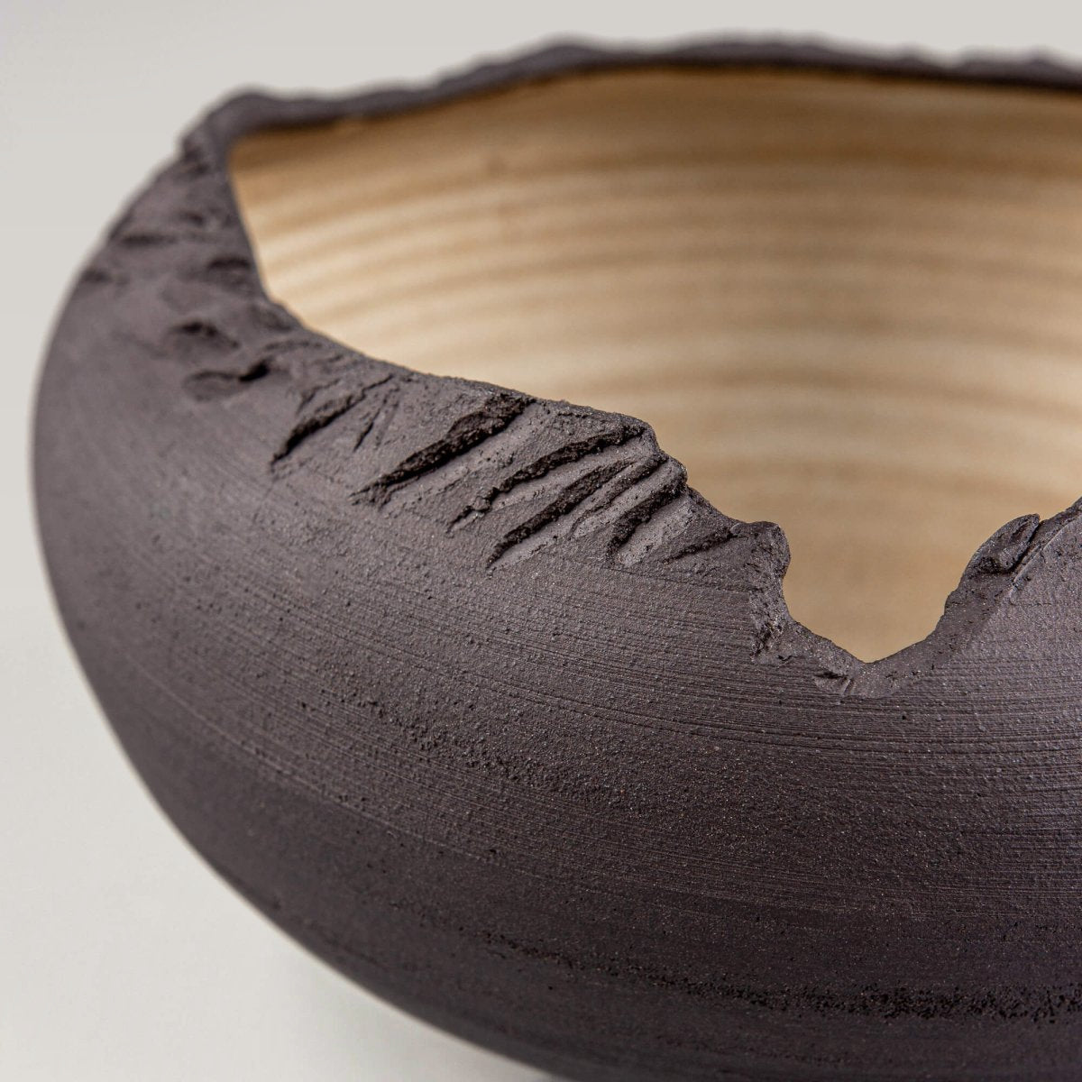 Detail shot of rugged hand-carved rim on matte black ceramic serving bowl.