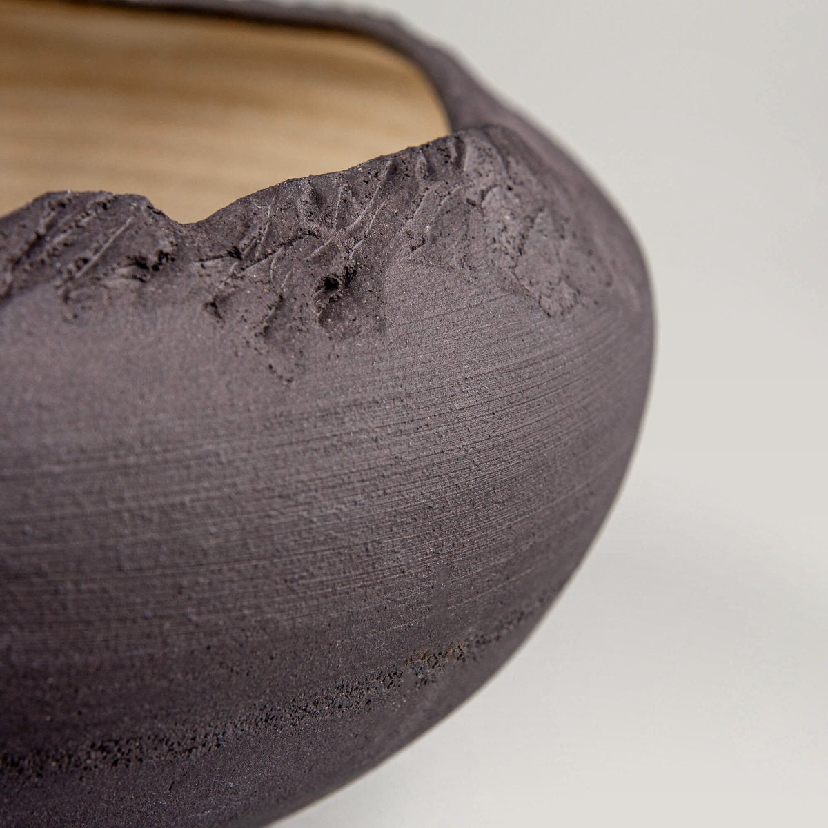 Close-up of contrast between matte black exterior and light golden interior on handmade bowl.