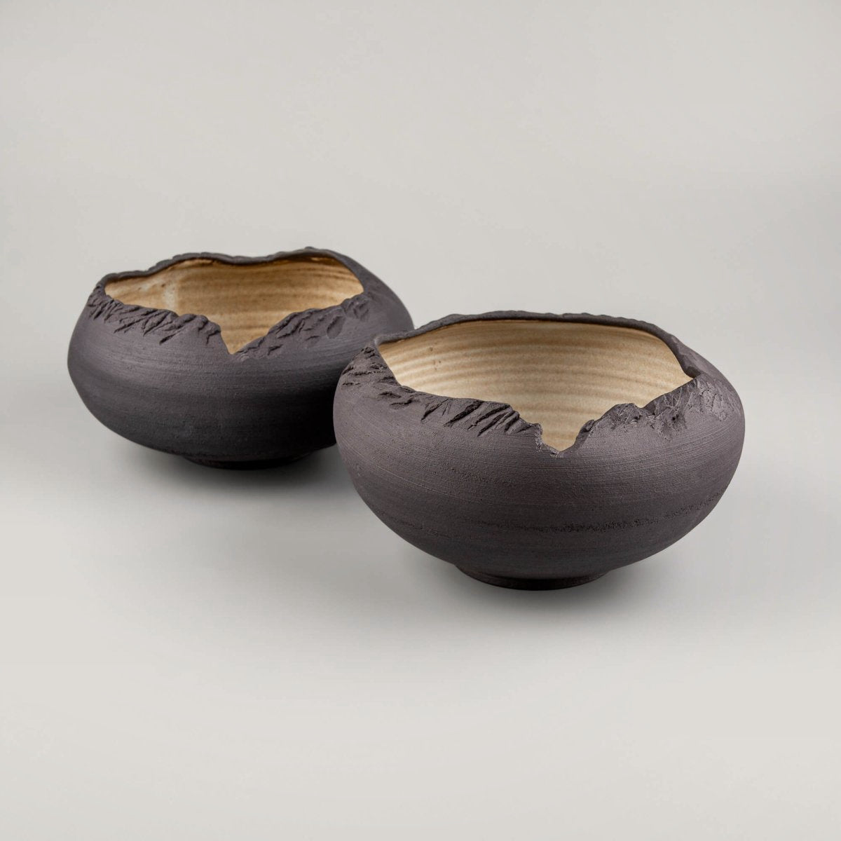 Pair of handmade stoneware bowls displaying variation in glaze and hand-textured surfaces.