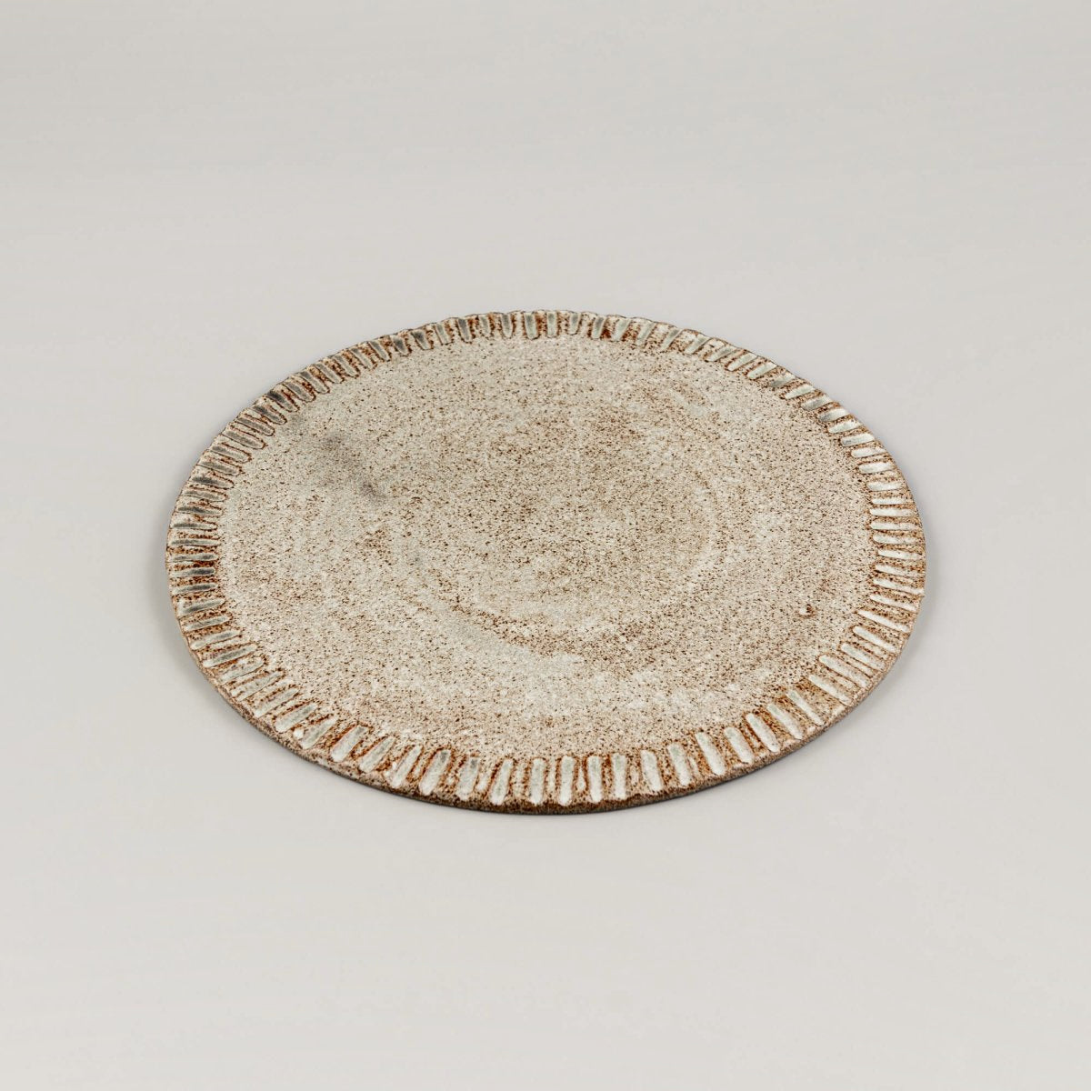 Flat handmade plate shown from side, highlighting refined stoneware form.