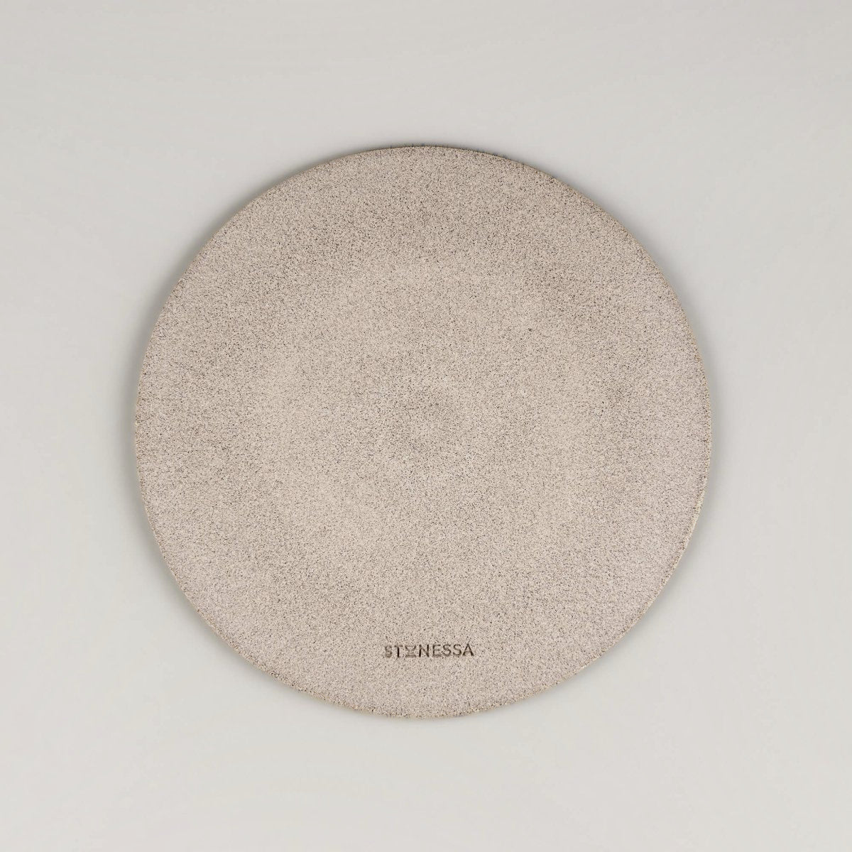 Backside of textured ceramic plate with raw clay base and carved finish.