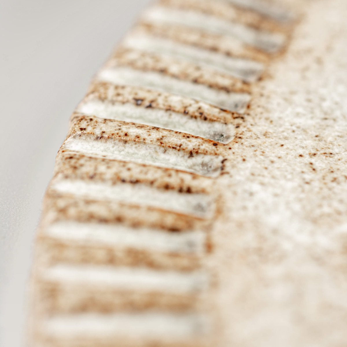 Detail of hand-carved edge on unique ceramic plate for collectors and stylists.