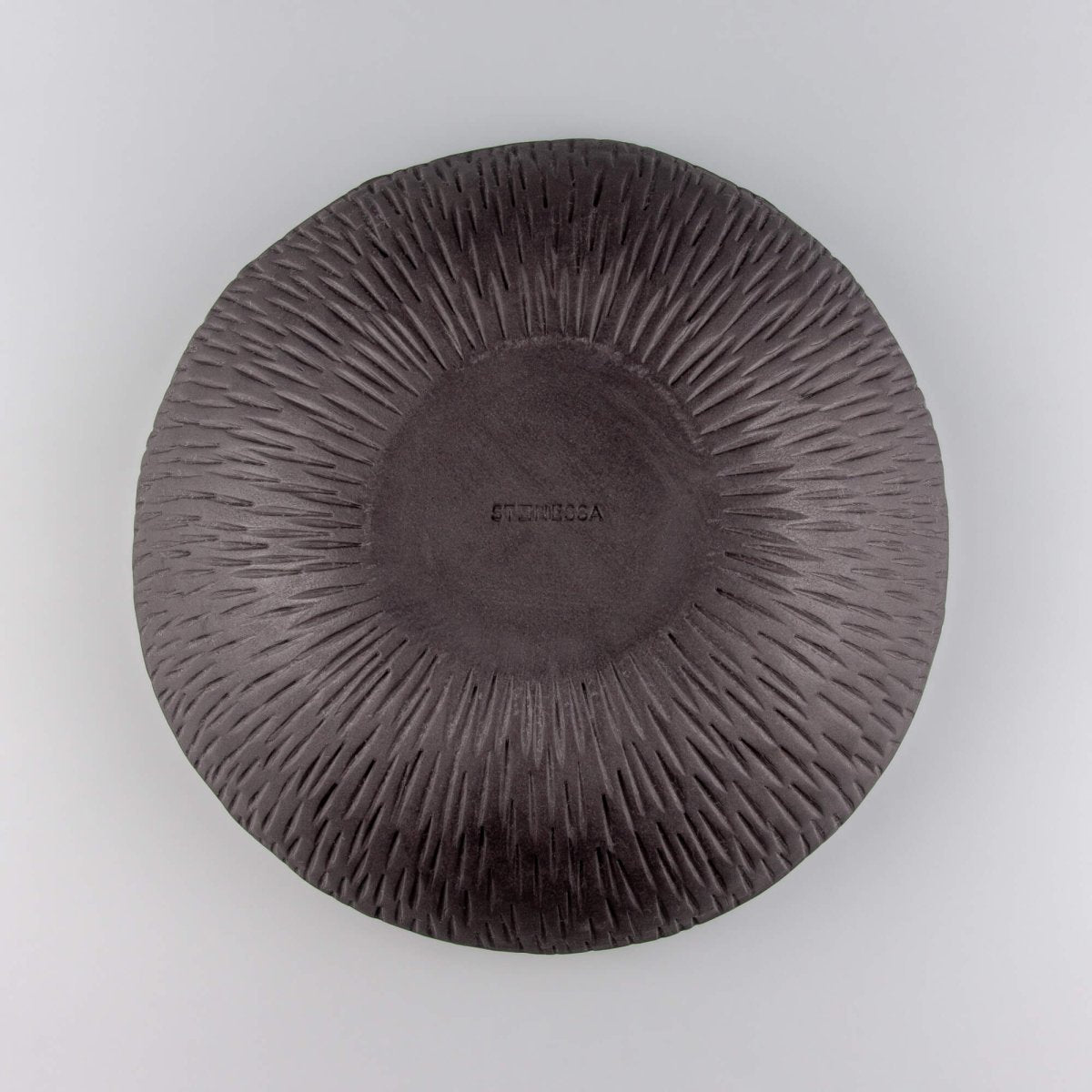 Bottom view of ceramic bowl made from black stoneware clay with matte unglazed base.