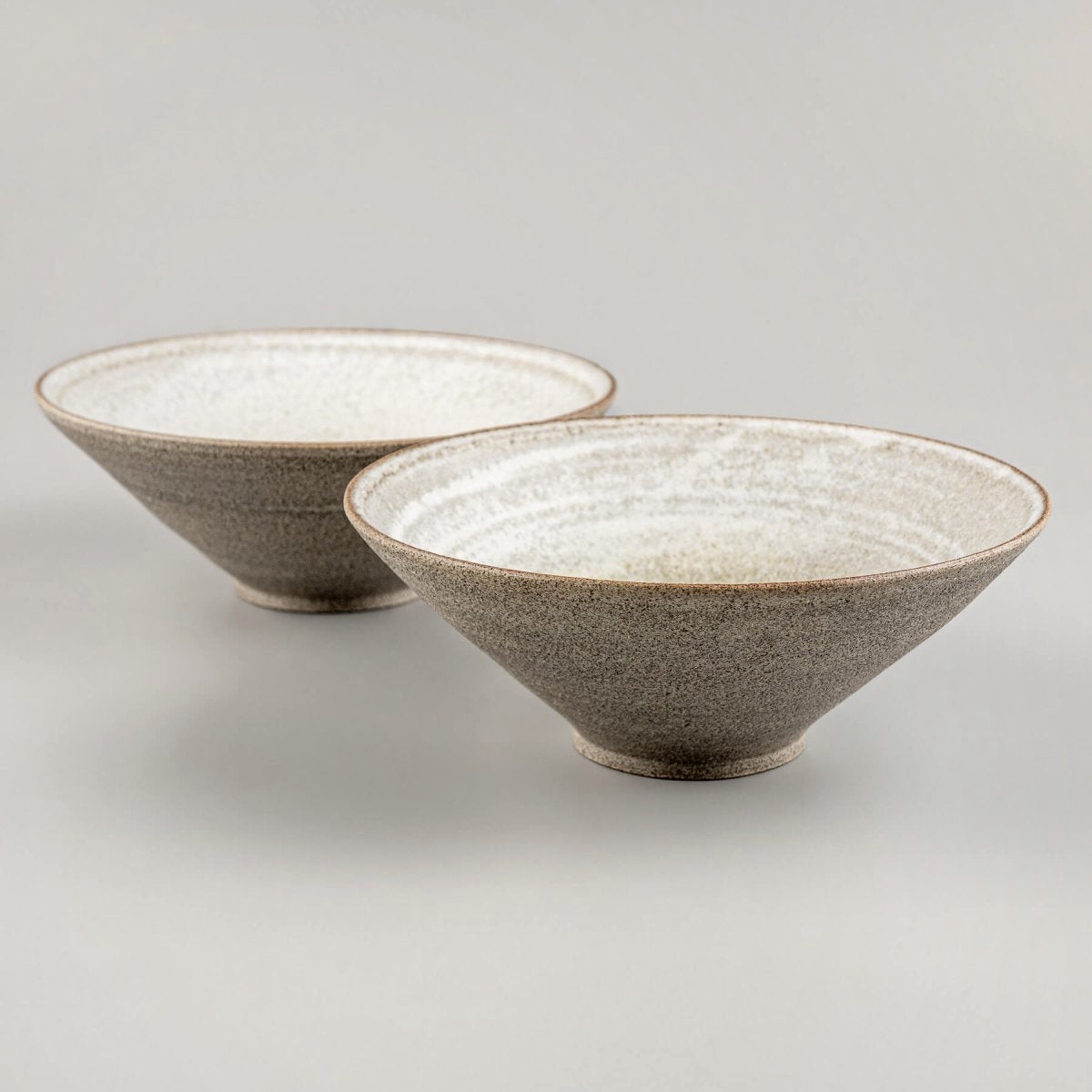 Pair of handmade stoneware bowls placed side-by-side to show natural ceramic variation.