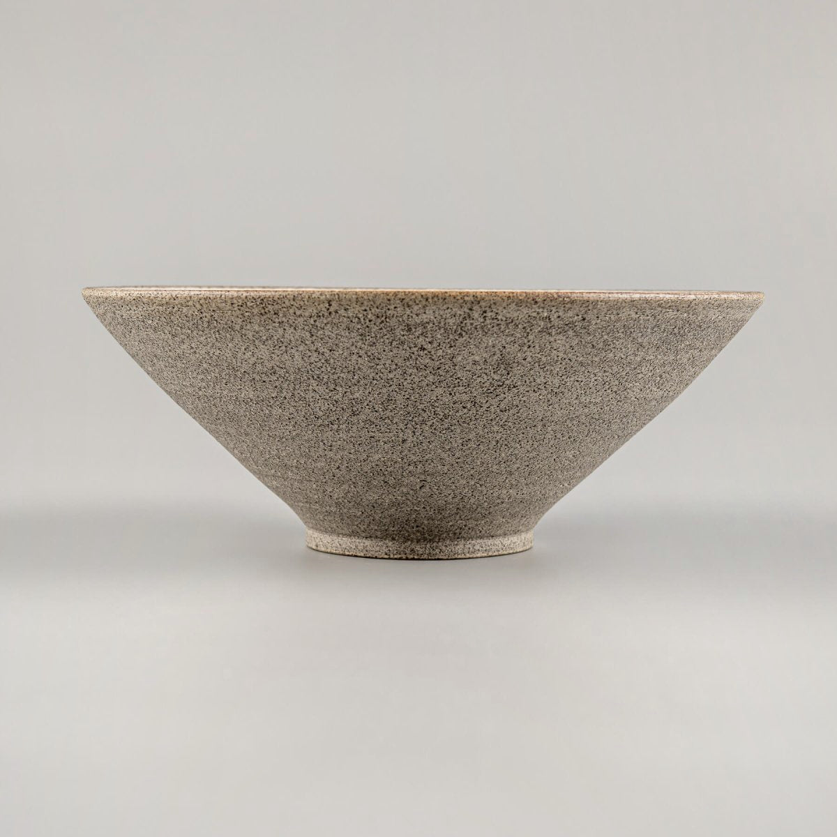 Back view of handcrafted ceramic bowl revealing natural unglazed base and curved form.