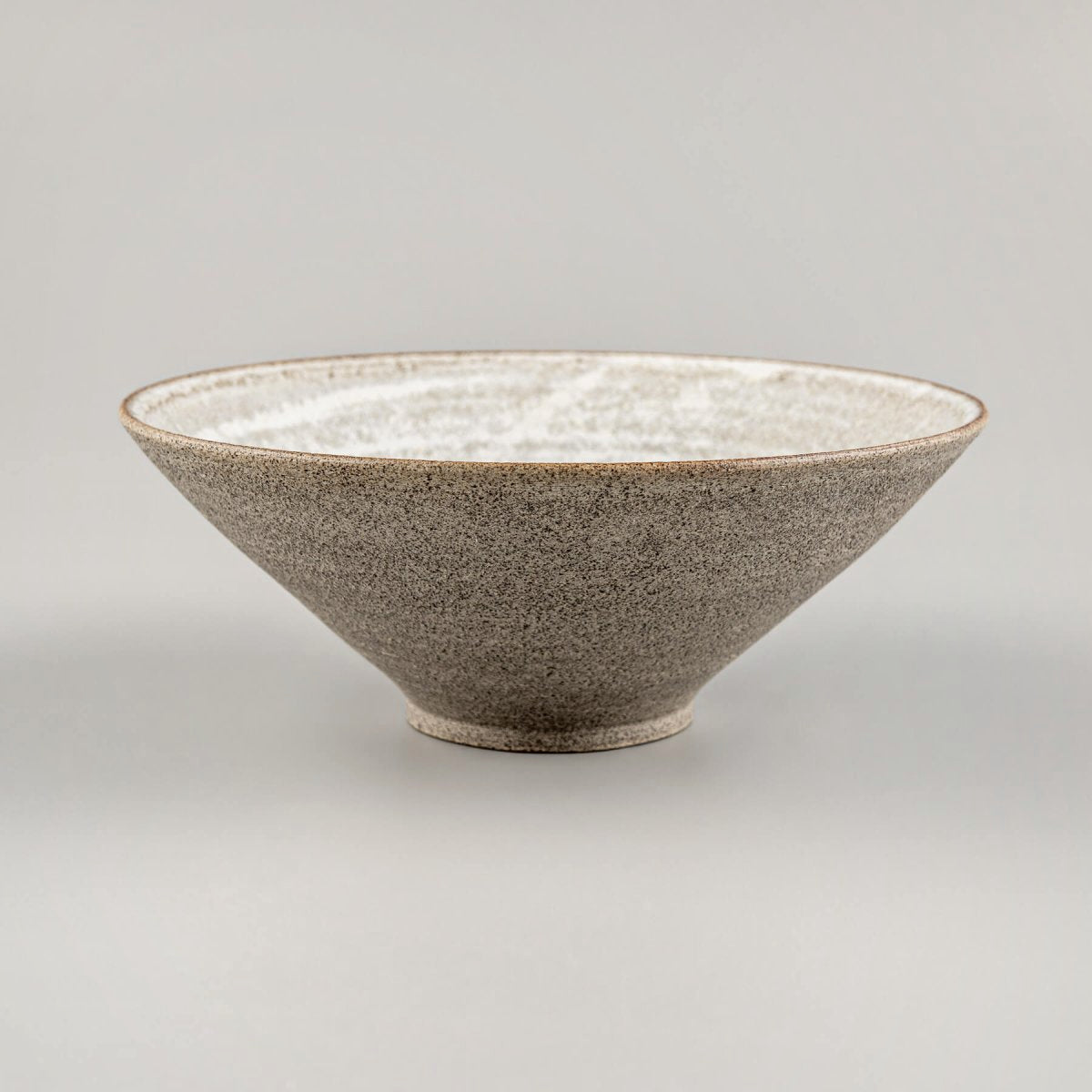 Side view of a handmade ceramic bowl with tall V-shaped profile and glazed stoneware surface.