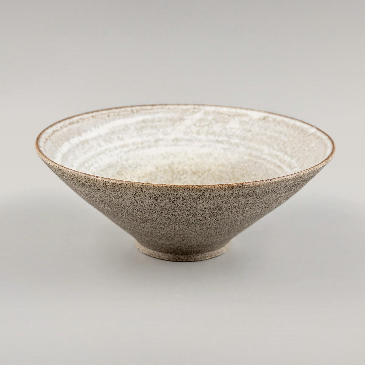 Sculptural ceramic bowl photographed diagonally to highlight its handmade, artisan shape.