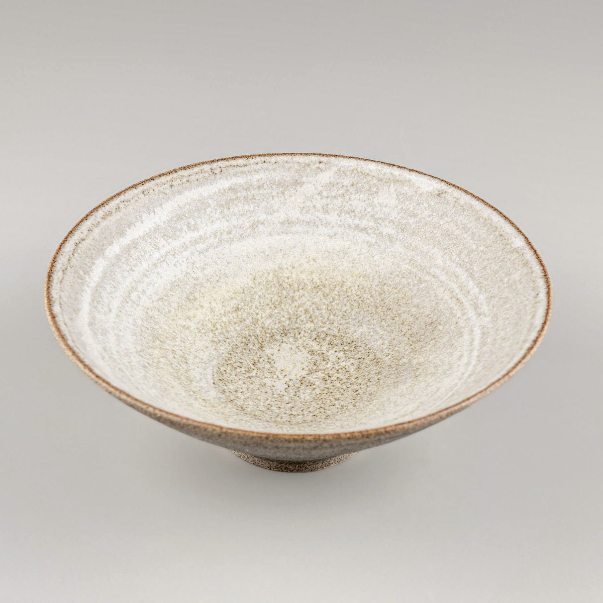 Angled front view of handmade pottery bowl with natural stoneware texture and high walls.