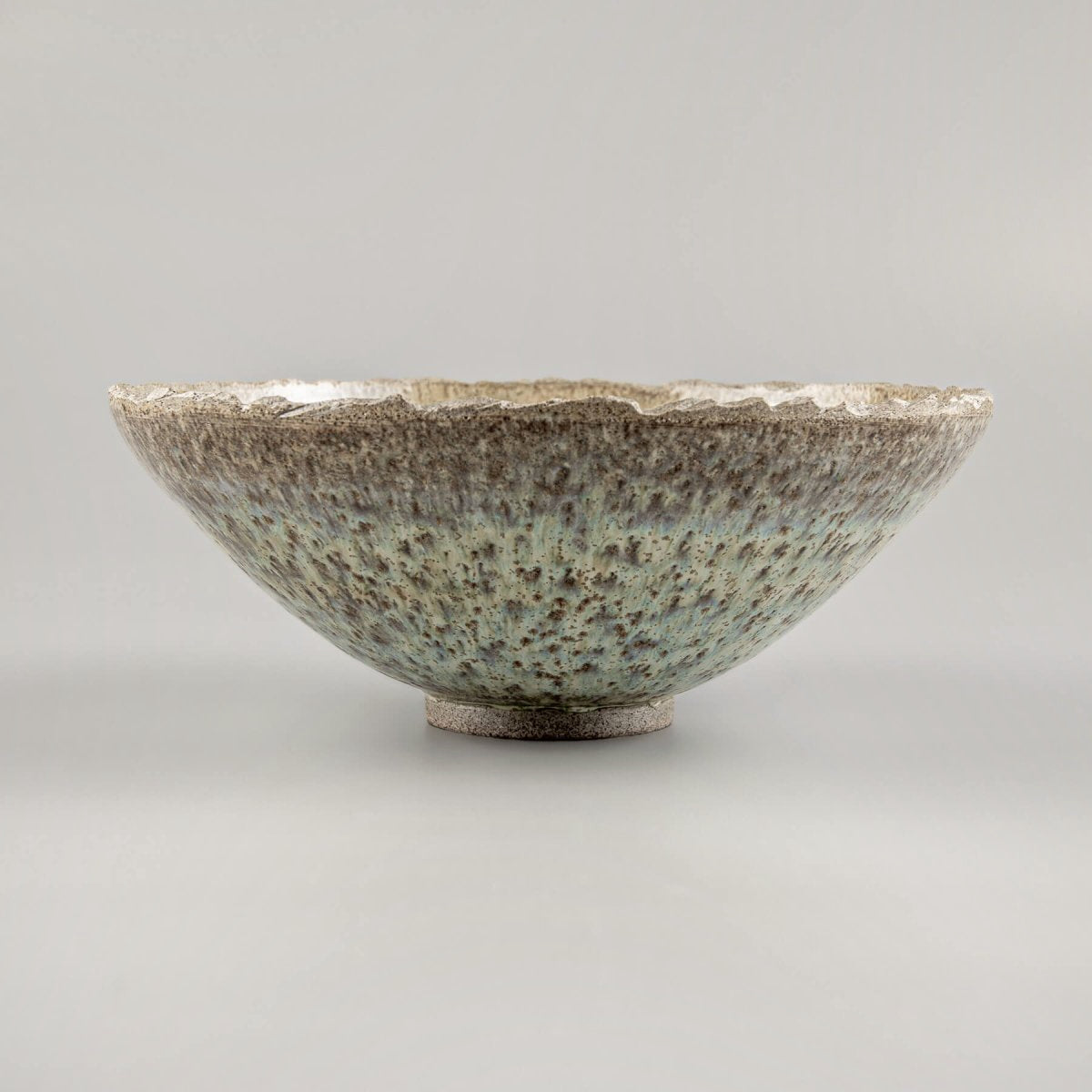 Profile view of artisan handmade ceramic bowl with curved edge and minimalist base.