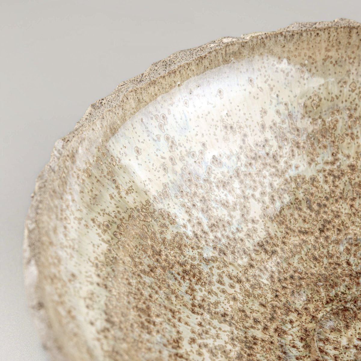 Detail of handmade stoneware bowl showing unique glaze and natural textured clay surface.