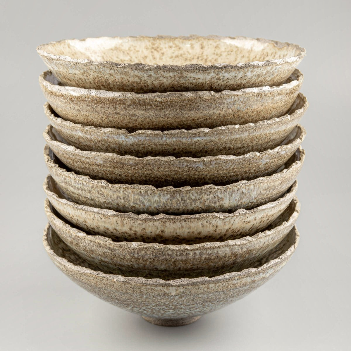 Group of handcrafted ceramic bowls showing unique glaze variations and rustic charm.
