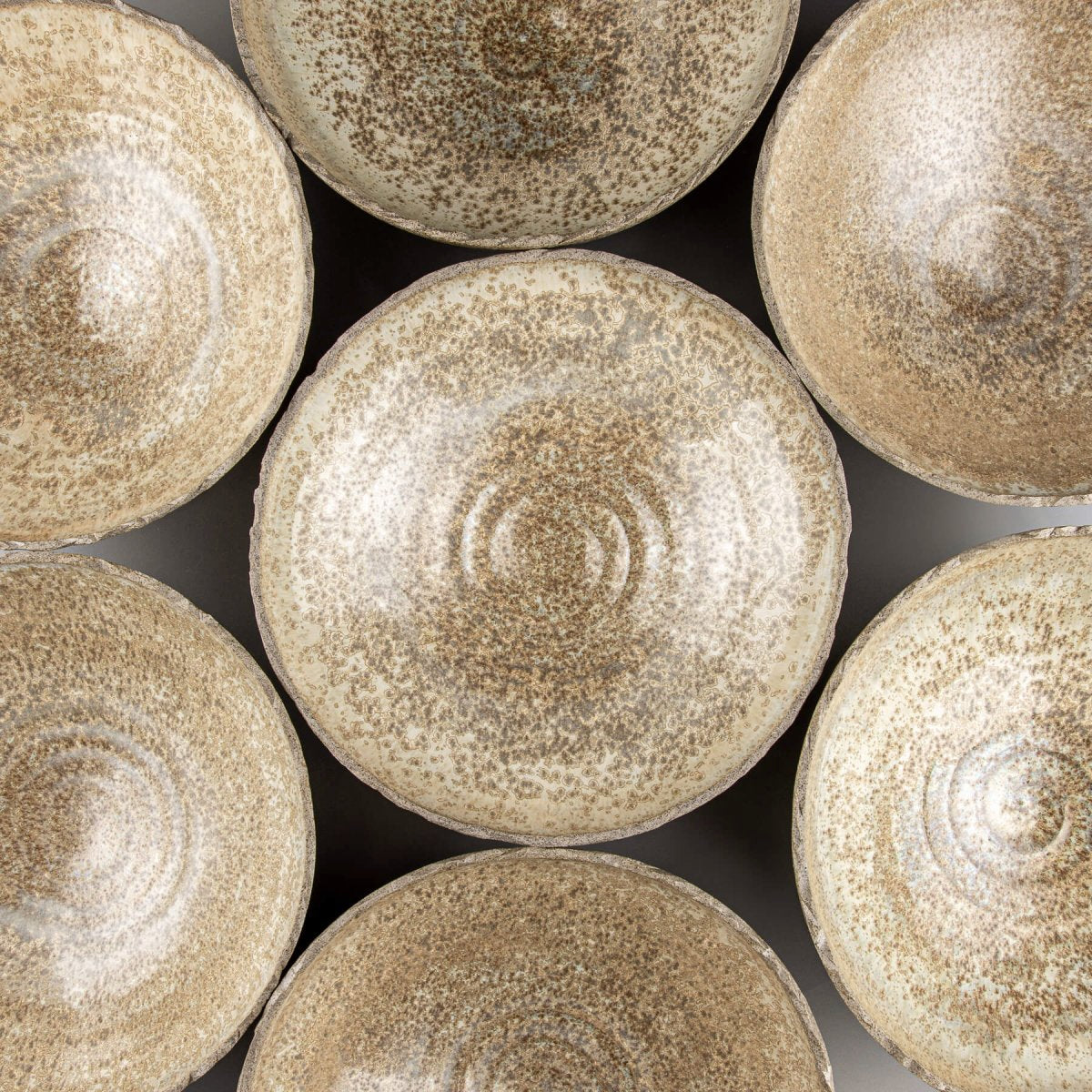 Close-up of handmade pottery bowls highlighting smooth glaze and natural stoneware texture.