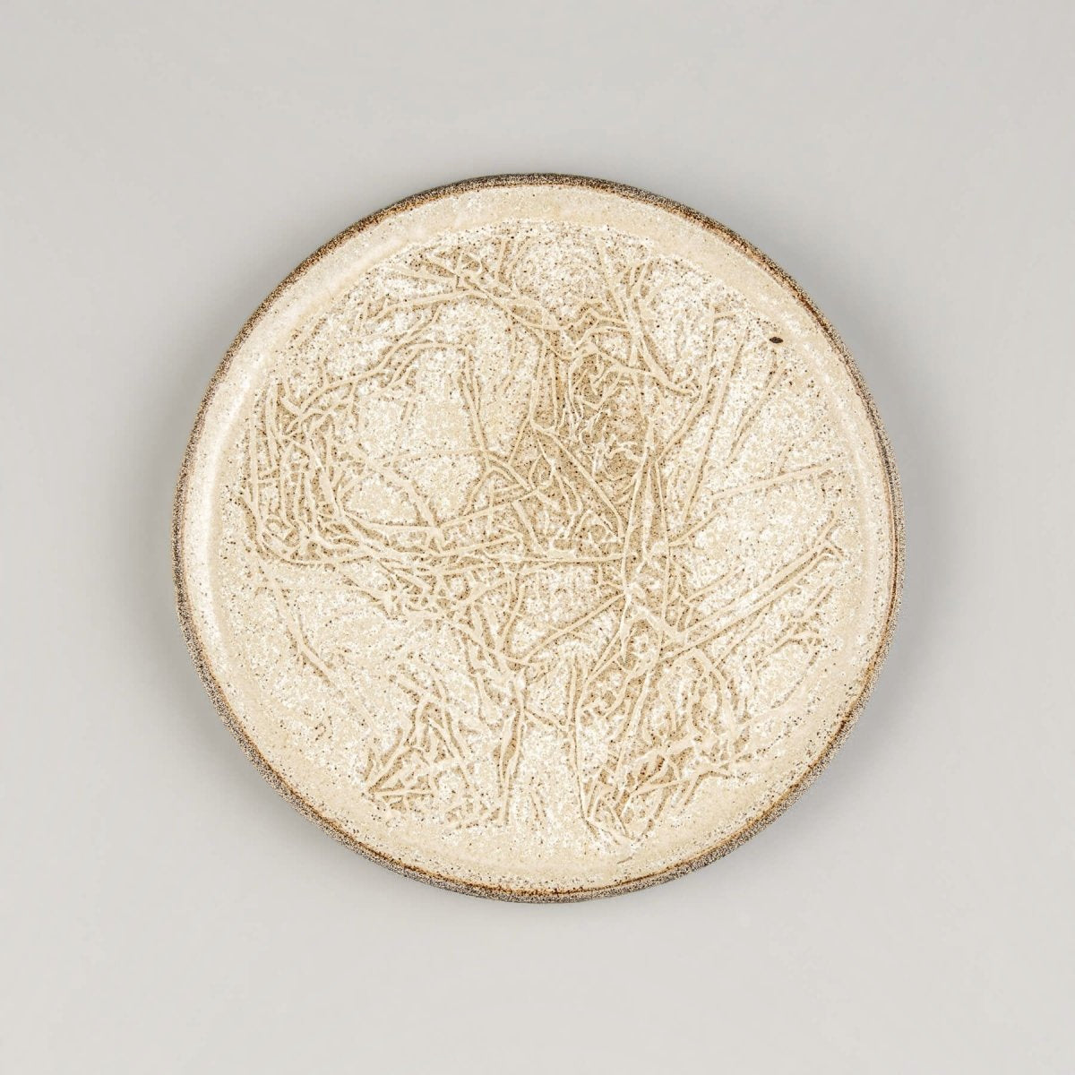 Handmade stoneware plate with embossed surface, ideal for serving desserts in fine dining settings.