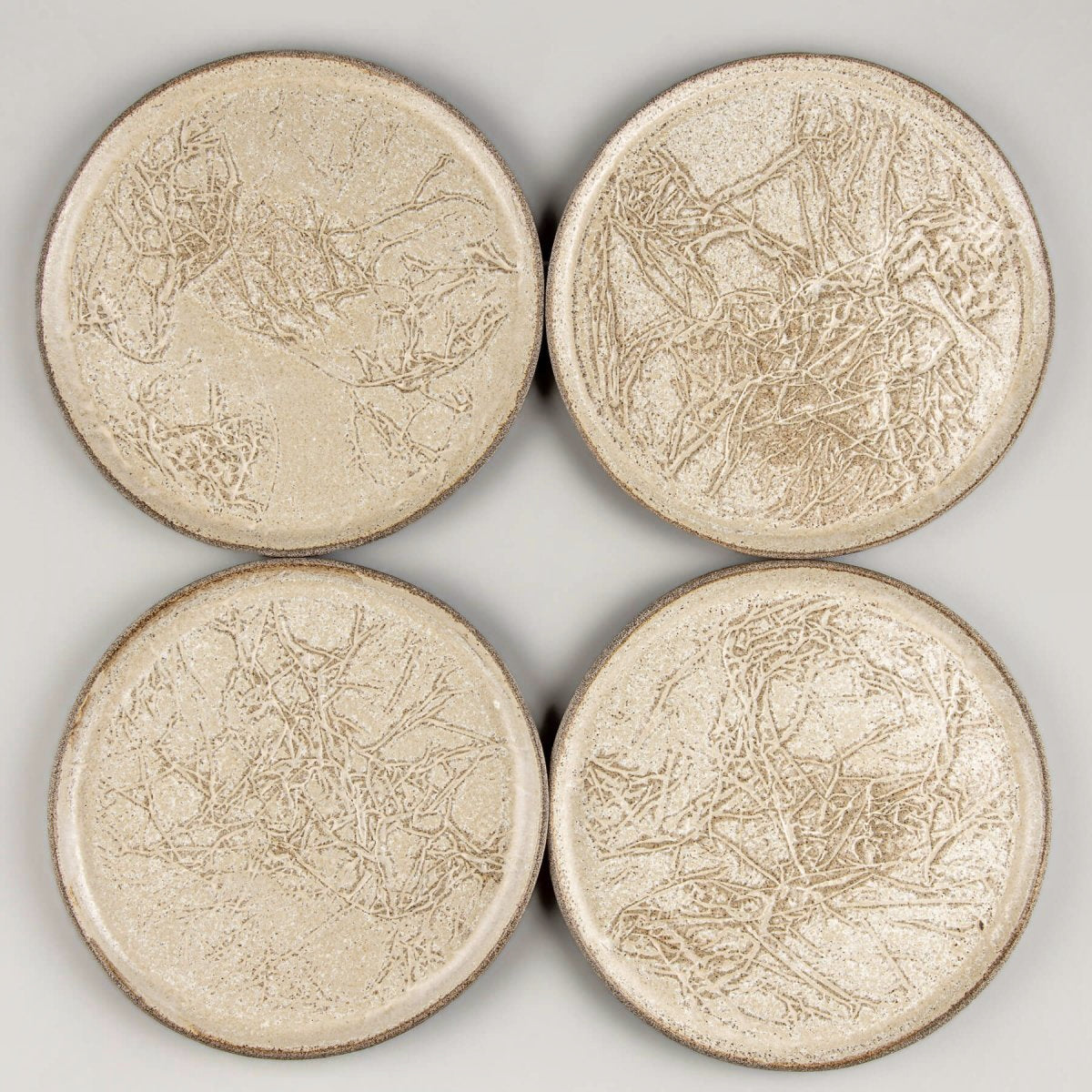 Four artisanal stoneware plates arranged for fine dining or home decor.