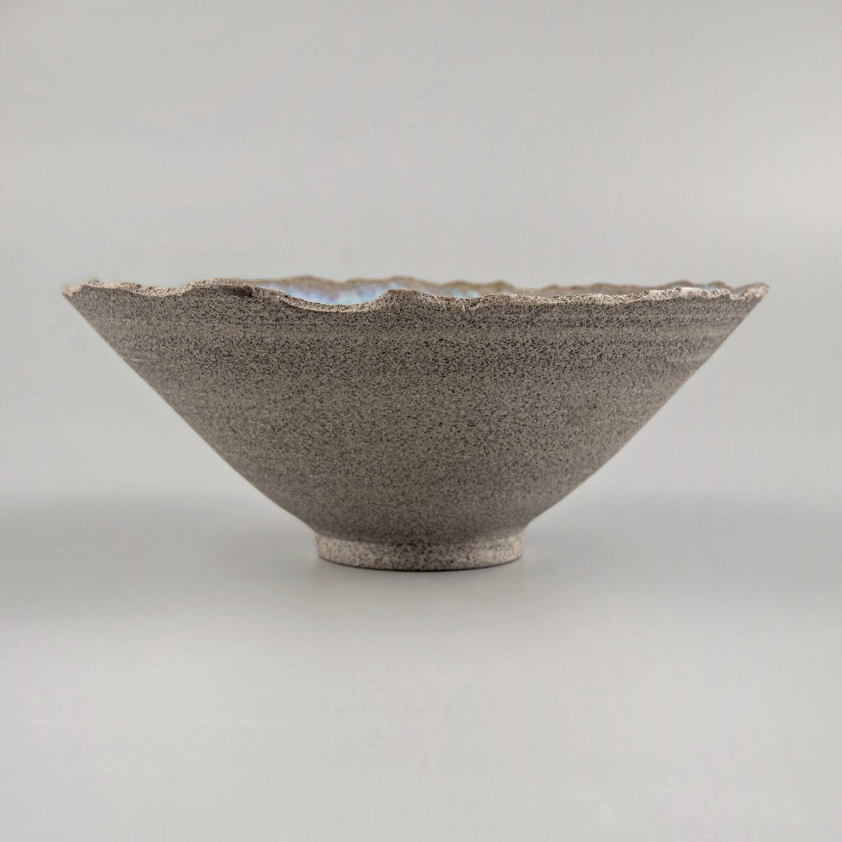 Profile view of artisan bowl emphasizing tall V-shaped form and footed base.