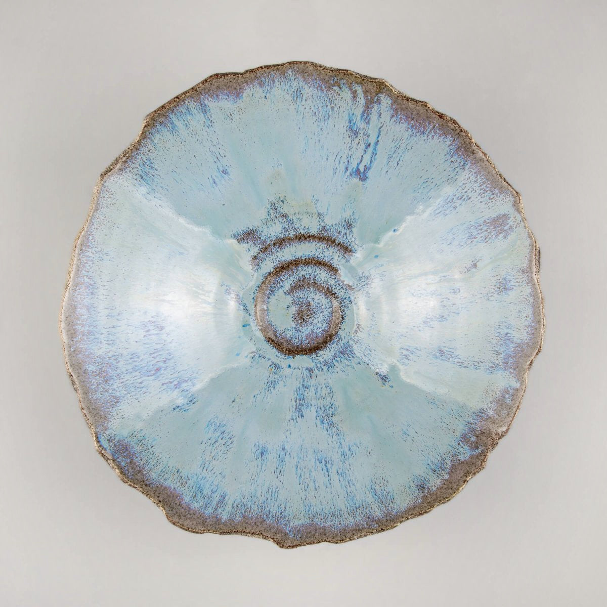 Top-down view of artisan stoneware bowl showing spiral detail and glossy blue finish.