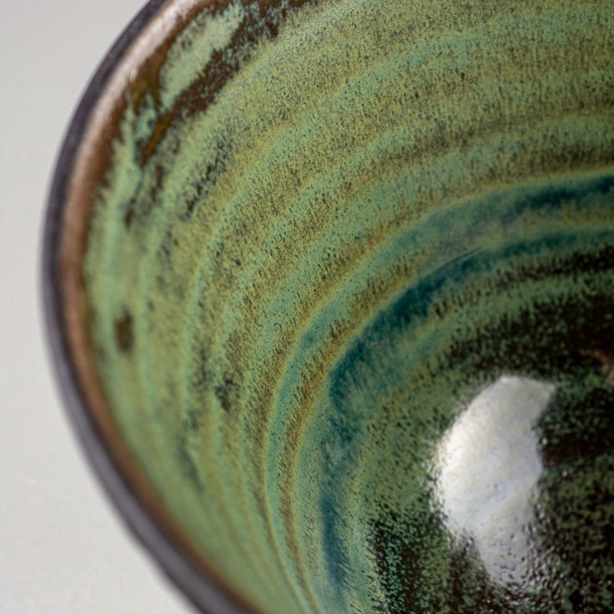 Close-up of green glazed ceramic surface with artistic pottery details.