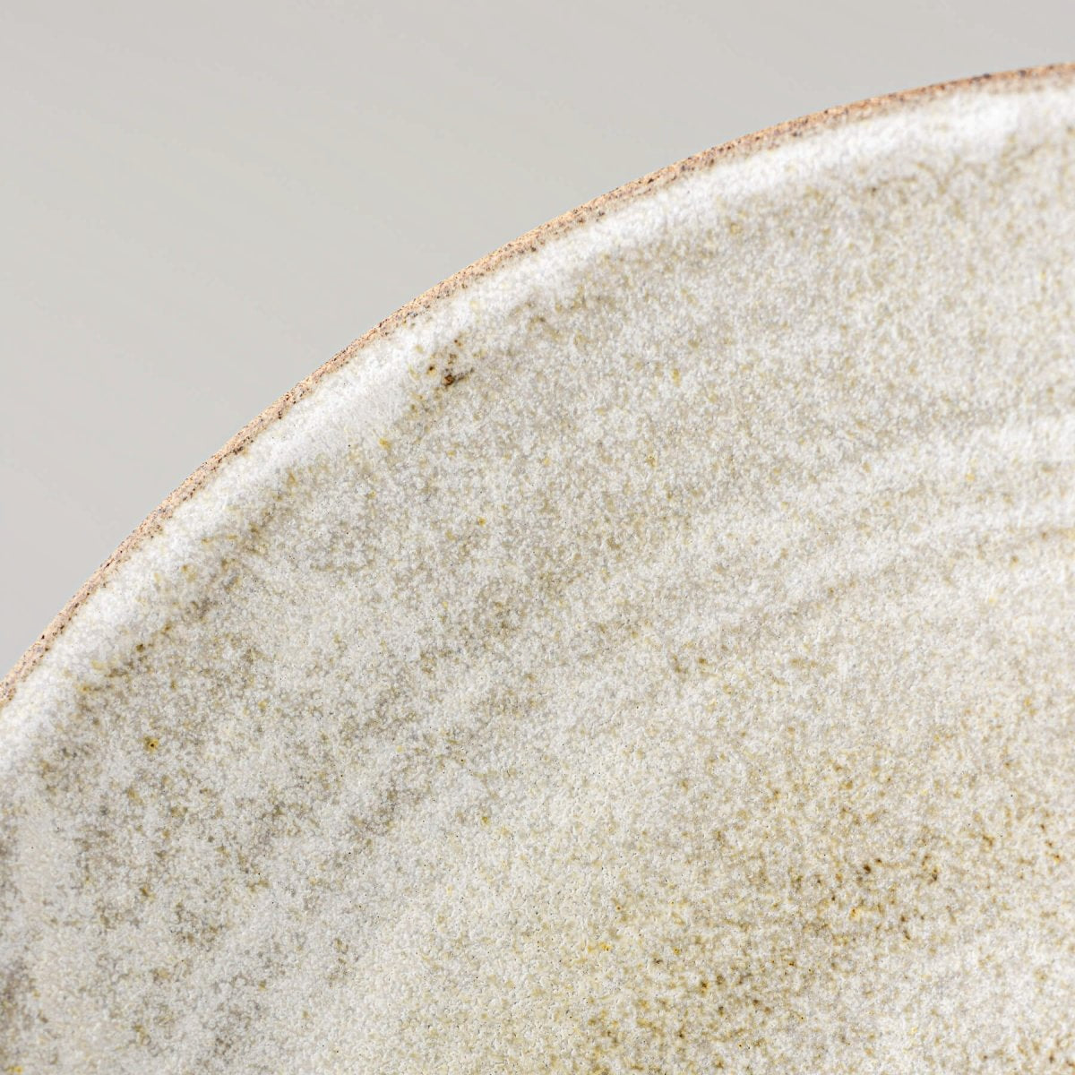 Macro shot of glazed rim and interior texture of artisan-crafted ceramic serving bowl.