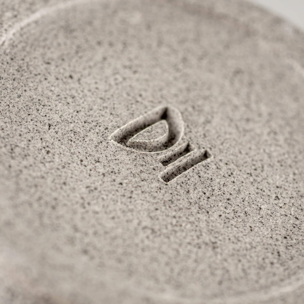 Bottom stamp detail showing artisan signature on handmade stoneware ceramic bowl.