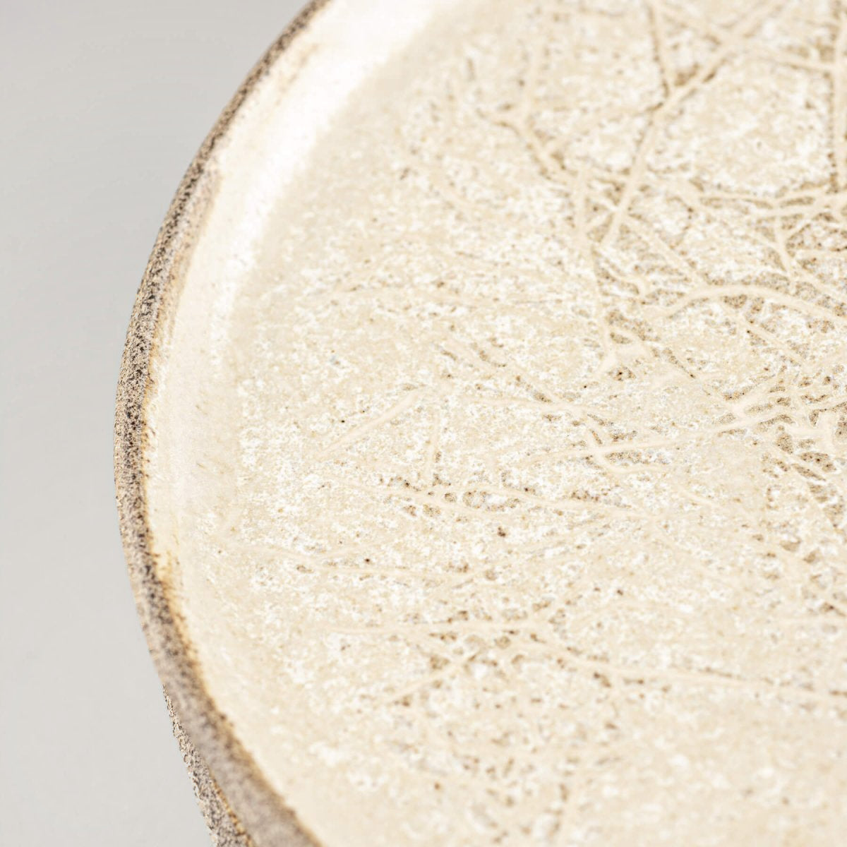 Flat stoneware plate with natural texture, suited for cheese or appetizers.