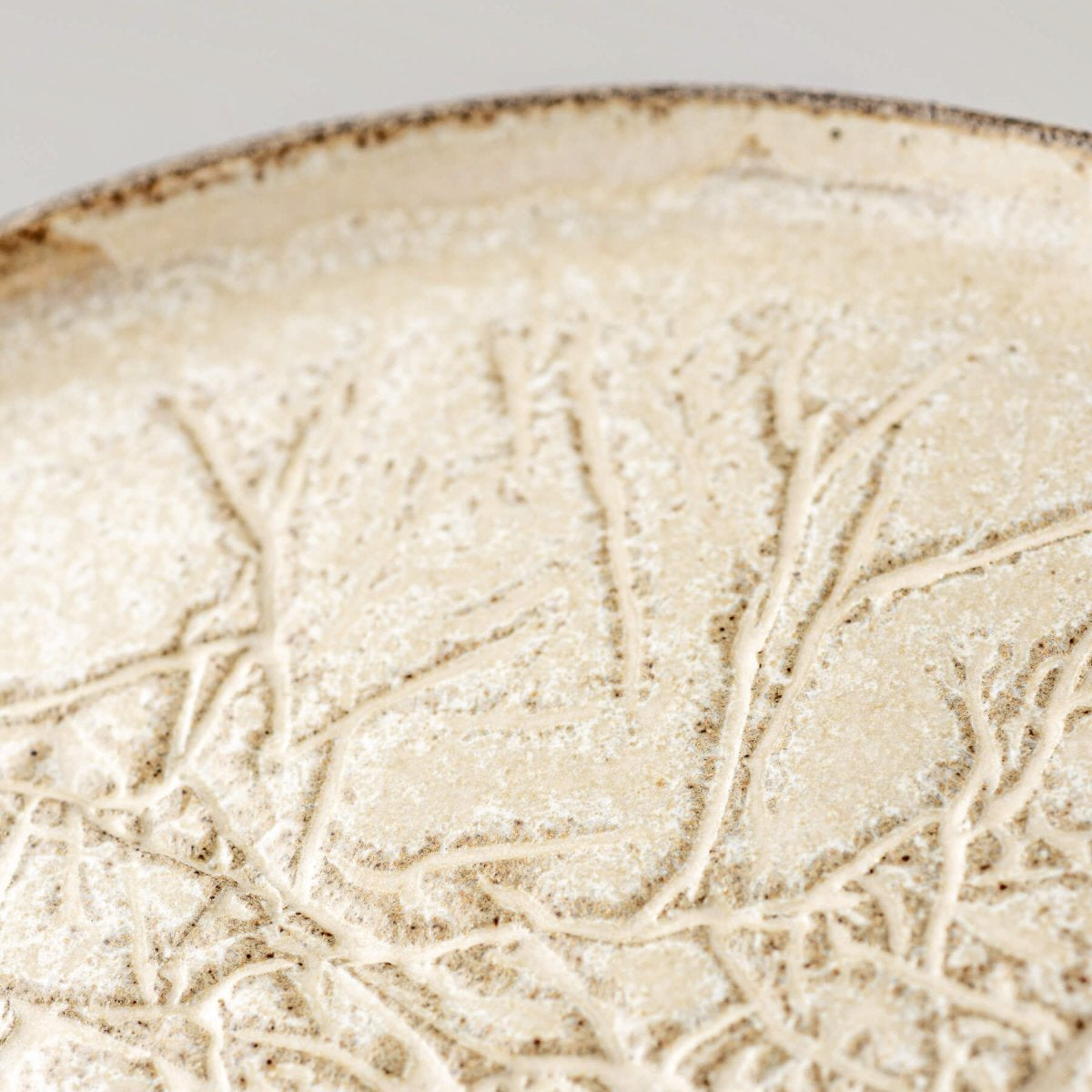 Close-up of artisanal surface pattern on decorative ceramic dinner plate.