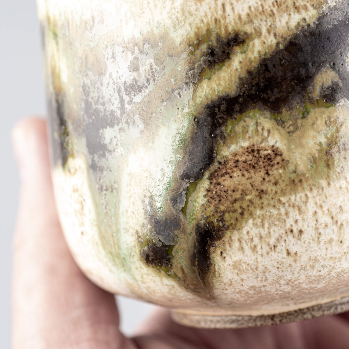 Close-up of stoneware mug glaze with luxury organic finish in earthy green and black tones.