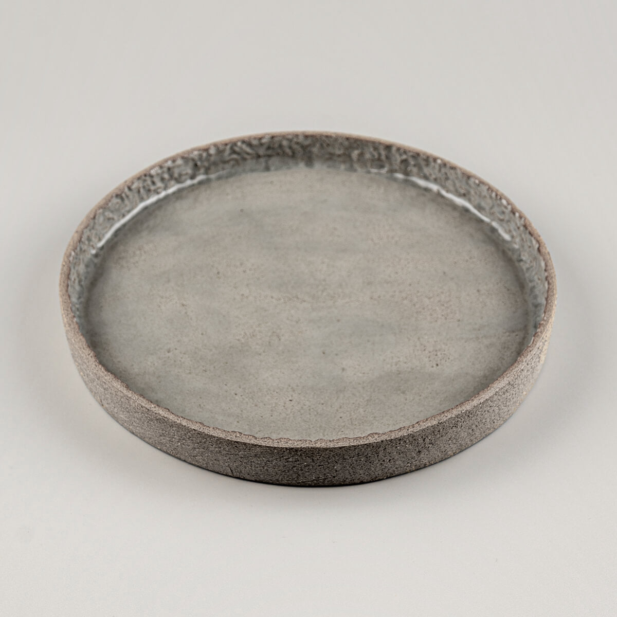 Top view of round ceramic plate with subtle carved detail and glossy artisanal finish.
