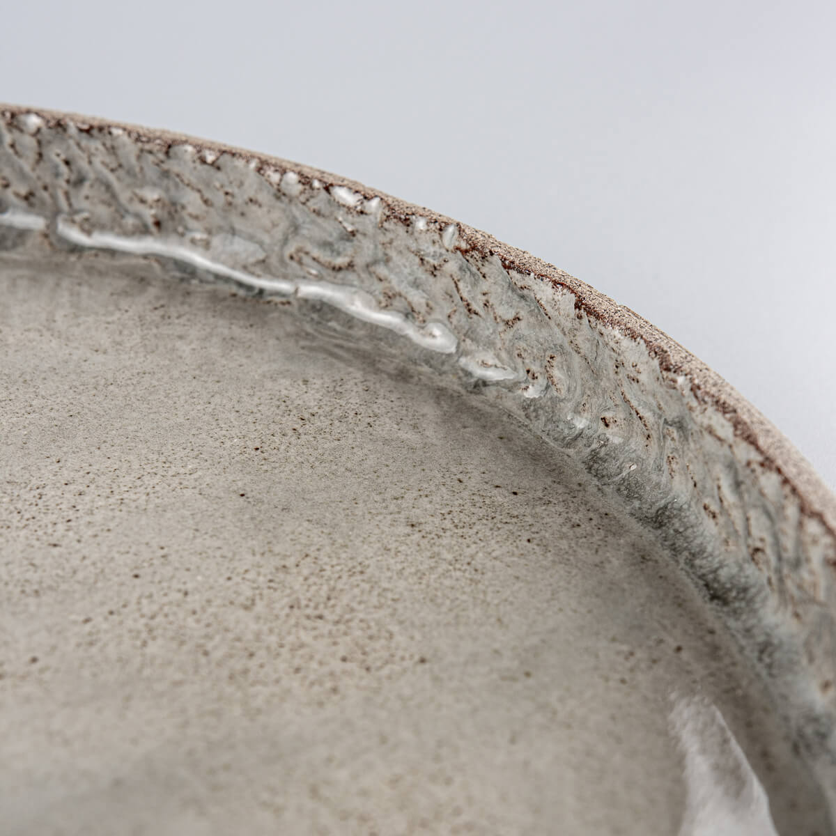 Detail of premium stoneware edge with artisanal carving and refined glaze finish.