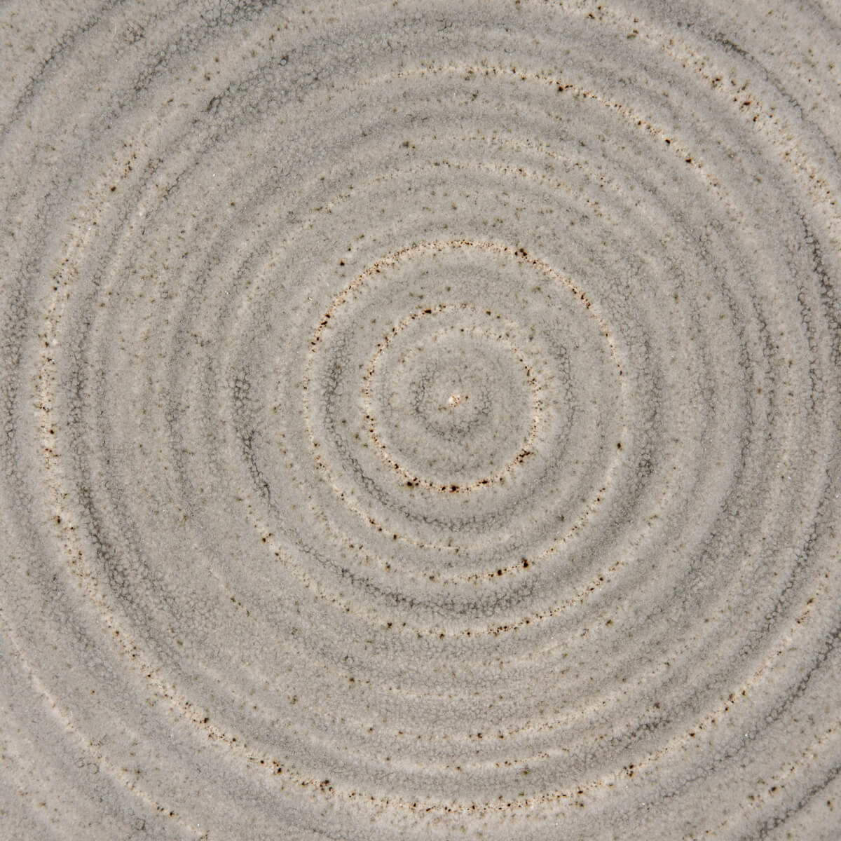 Detailed spiral texture on handmade ceramic plate, ideal for boutique hotels.