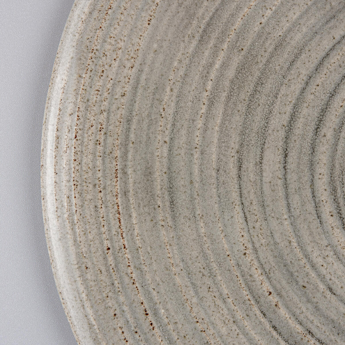 Close-up of stoneware plate showing matte and glossy glaze contrast for interior design.