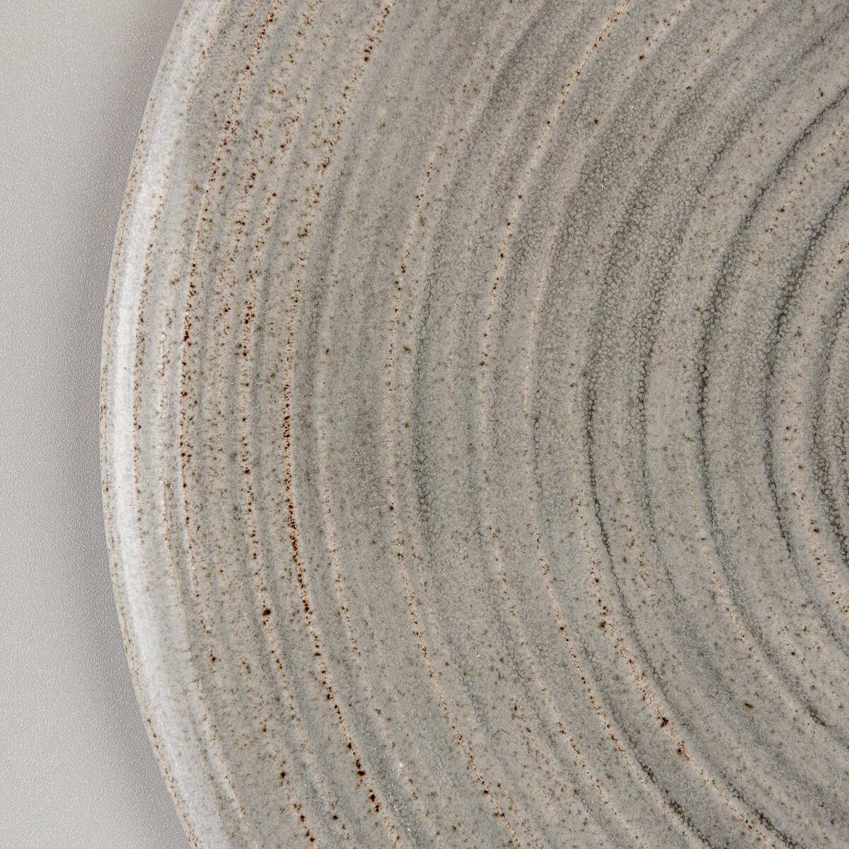 Close-up of stoneware plate showing matte and glossy glaze contrast for interior design.