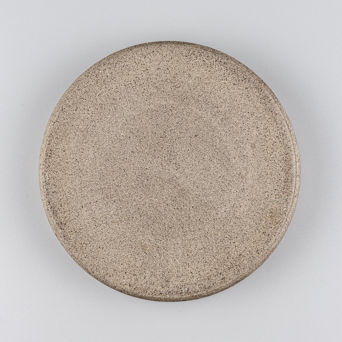 Backside of handcrafted plate highlighting unglazed base and earthy ceramic texture.
