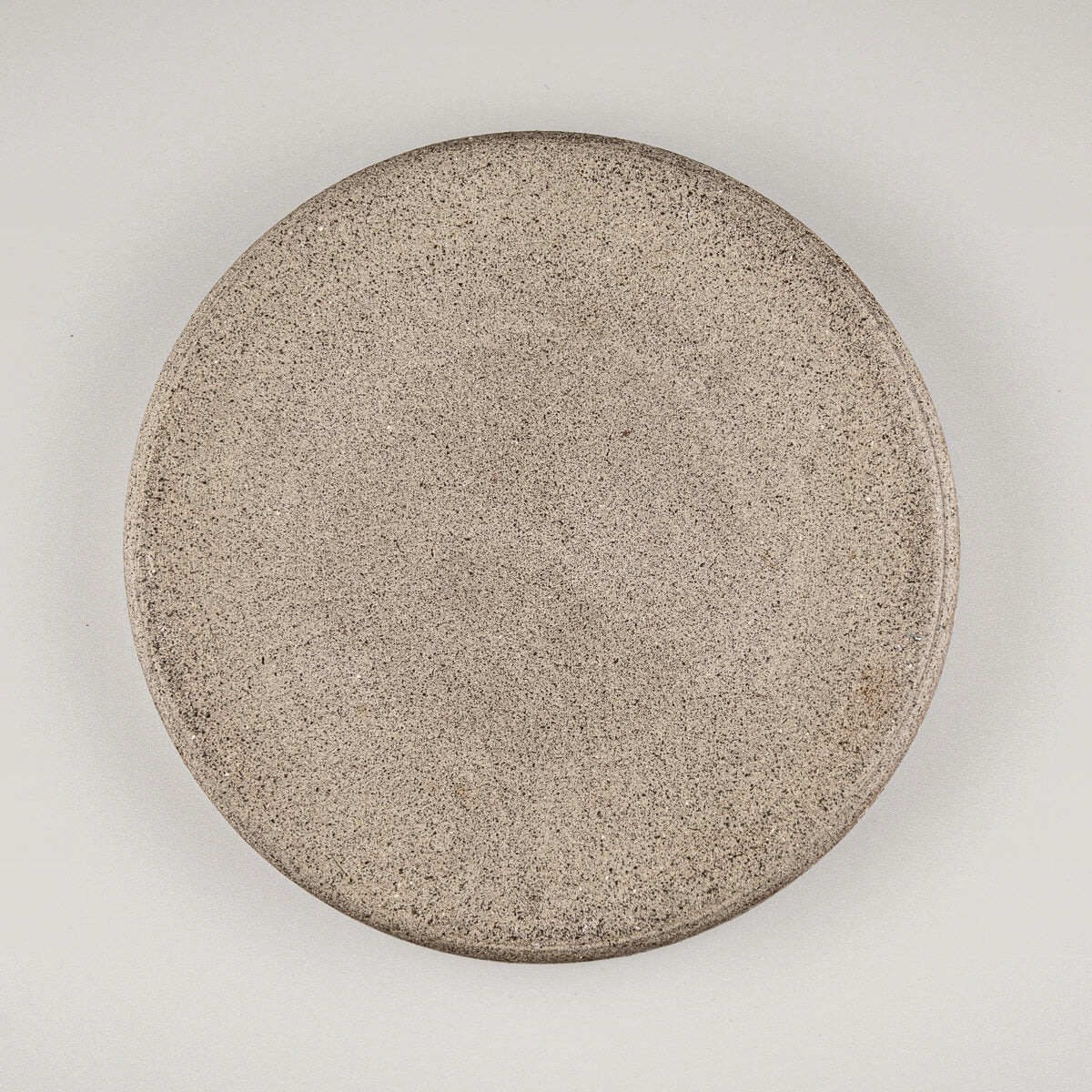 Backside of handcrafted plate highlighting unglazed base and earthy ceramic texture.