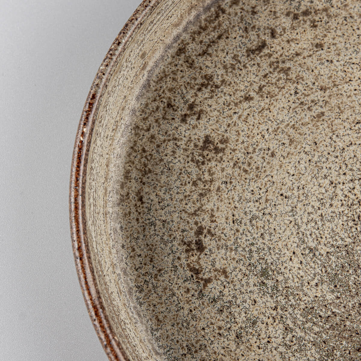 Detail of elevated rim on rustic stoneware plate designed for culinary presentation or gift use.