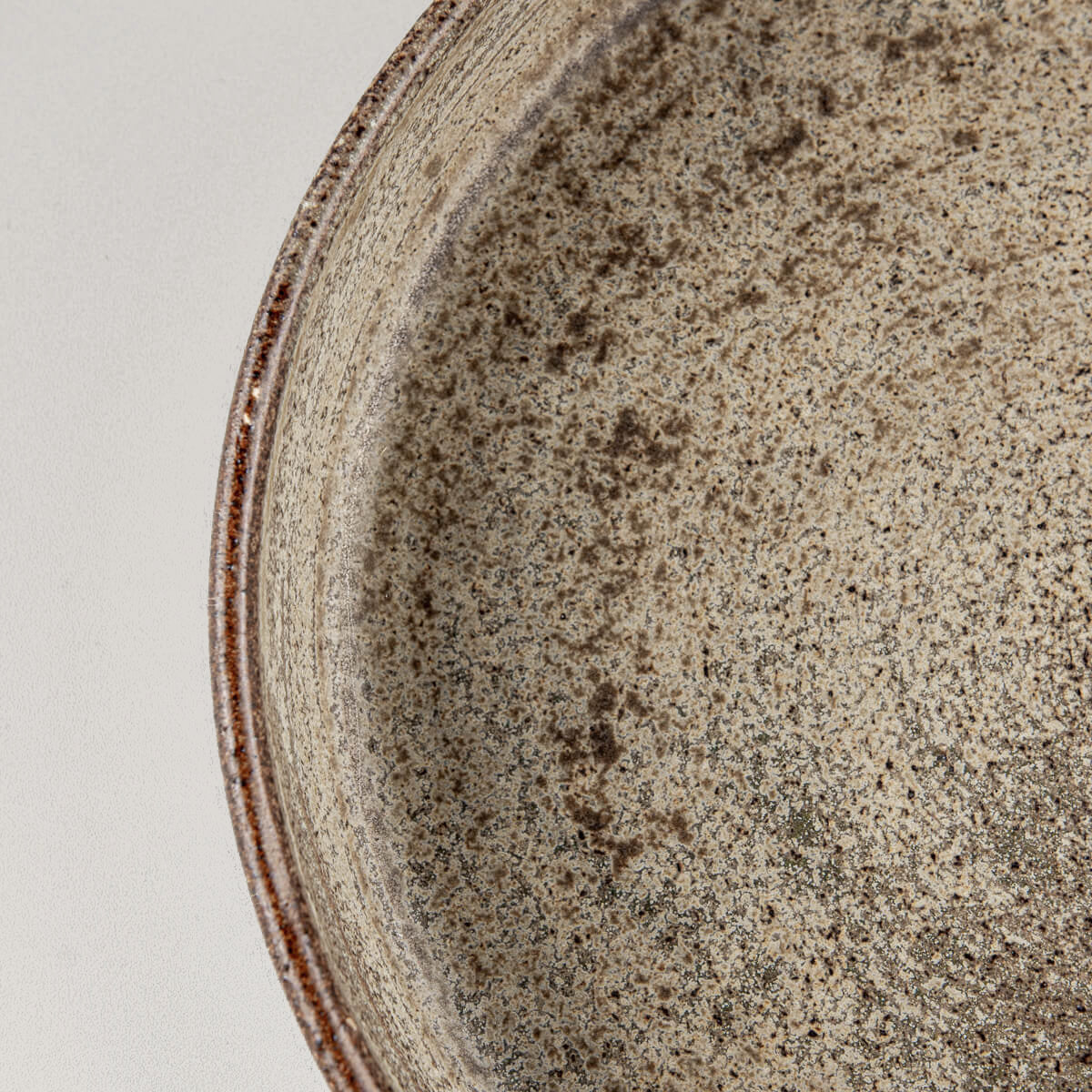 Detail of elevated rim on rustic stoneware plate designed for culinary presentation or gift use.