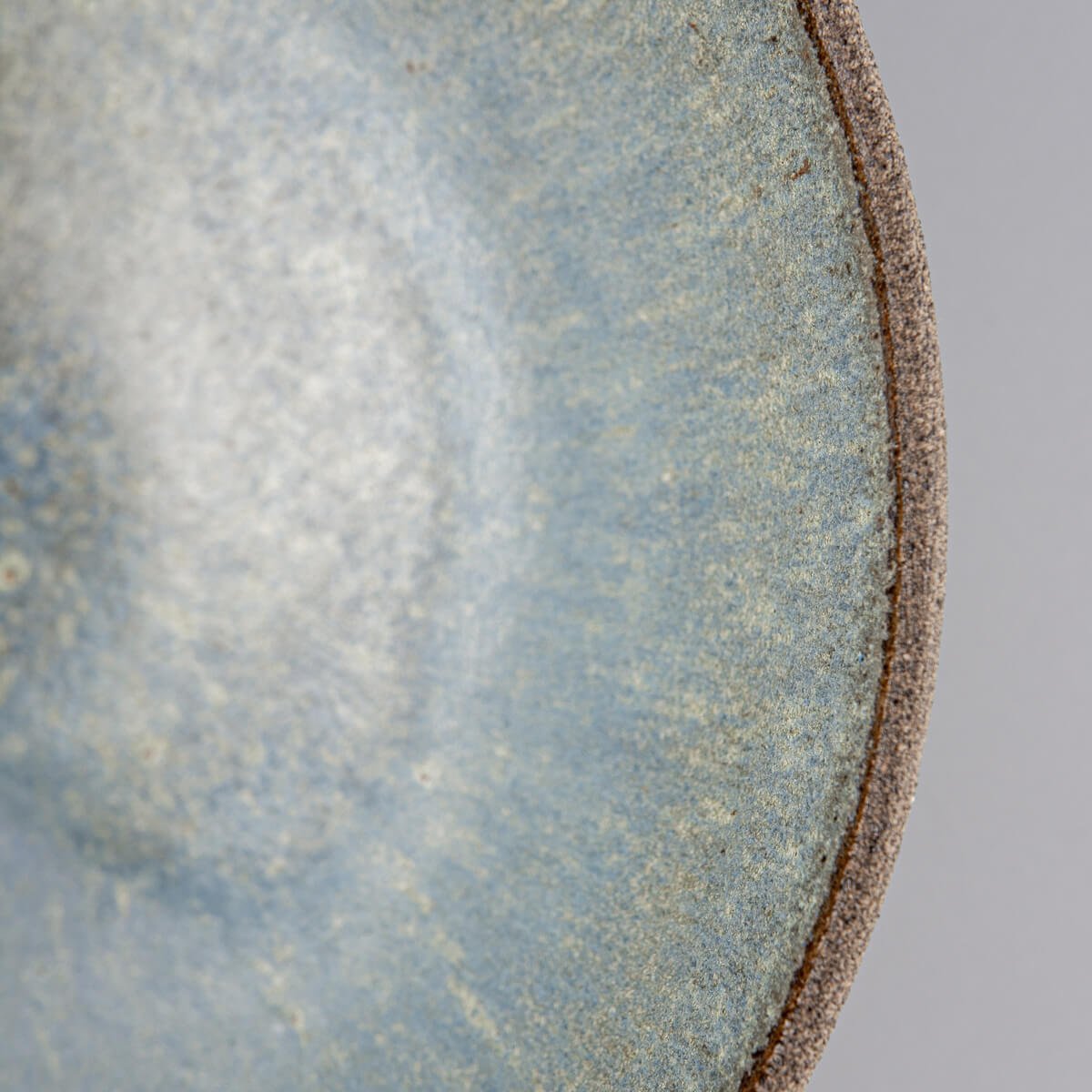 Close-up of interior glaze showing blue speckled pattern on handmade ceramic bowl.
