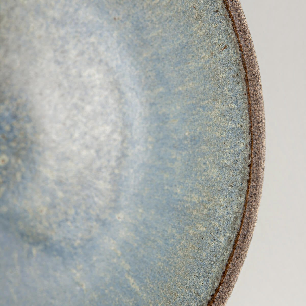 Close-up of interior glaze showing blue speckled pattern on handmade ceramic bowl.