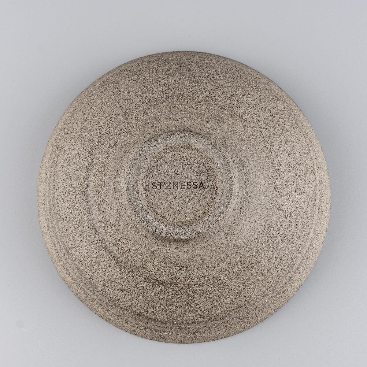 Bottom view of handmade ceramic bowl showing textured foot and artisan stamp detail.