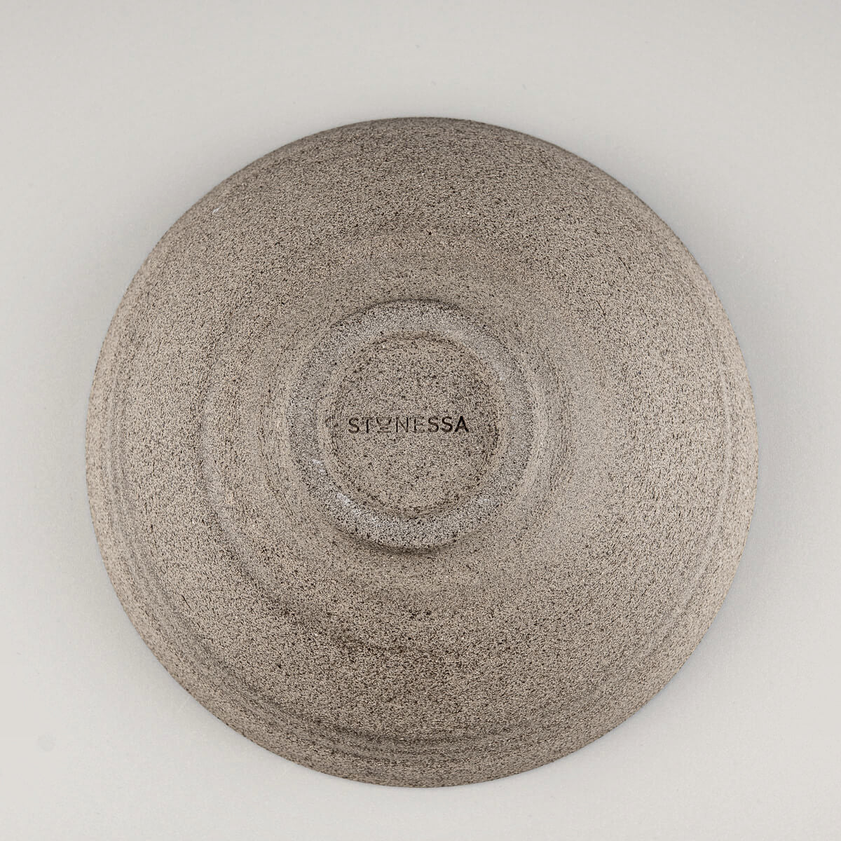Bottom view of handmade ceramic bowl showing textured foot and artisan stamp detail.