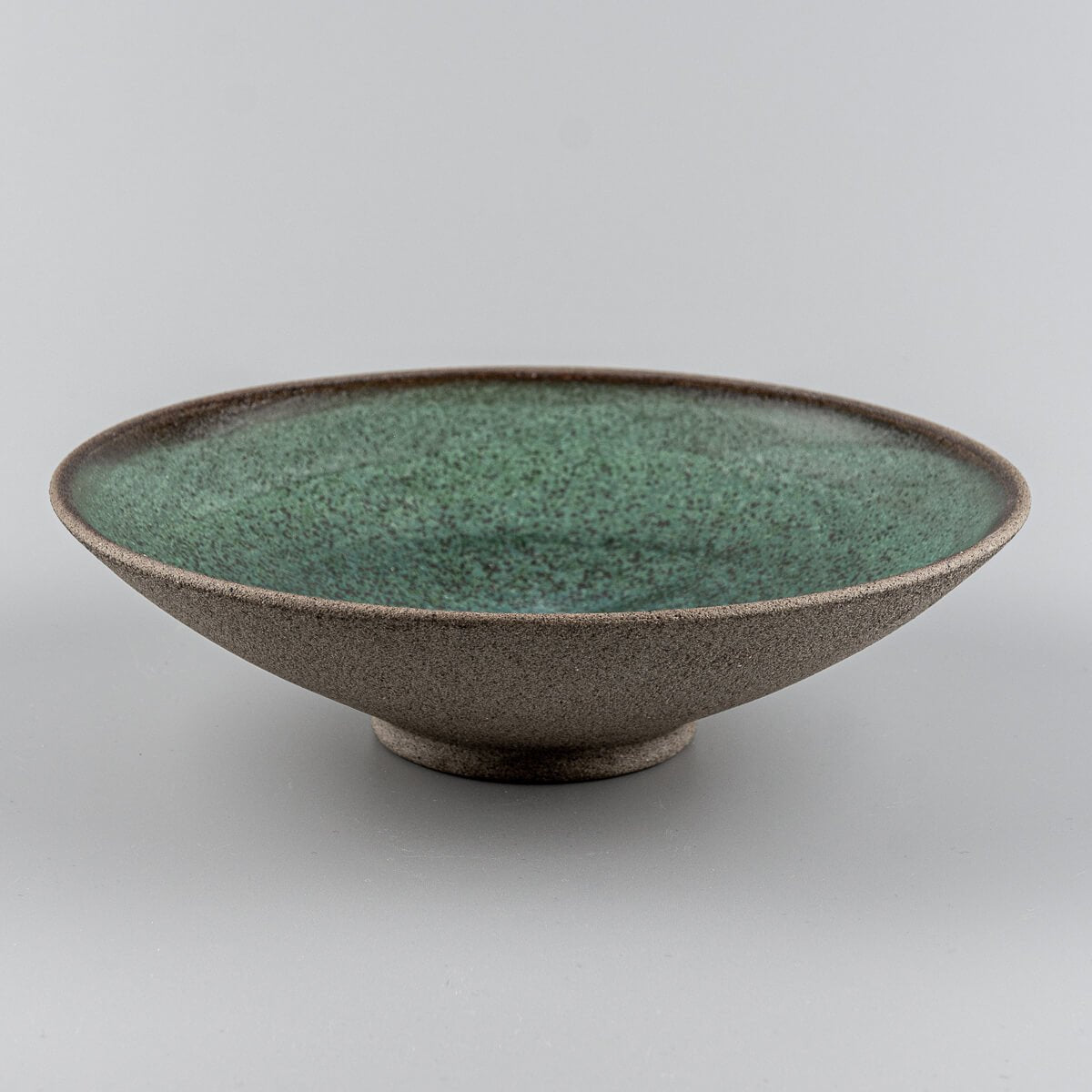 Angled profile of handcrafted stoneware plate for boutique restaurants or modern homes.