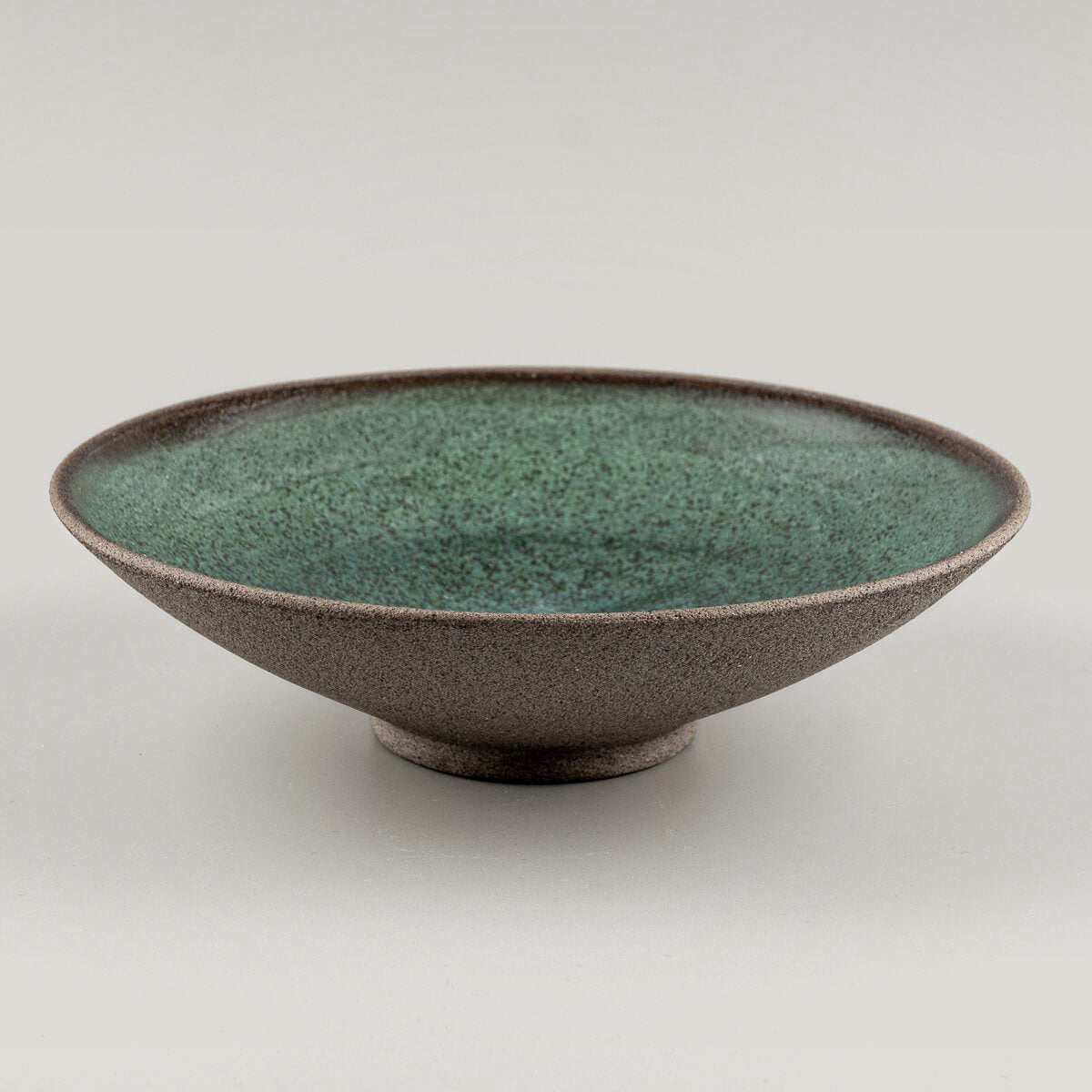 Angled profile of handcrafted stoneware plate for boutique restaurants or modern homes.