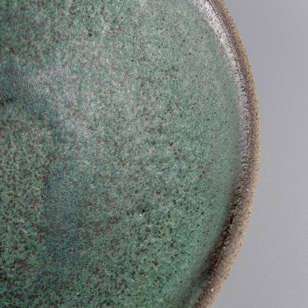 Close-up of green speckled ceramic surface perfect for fine dining and artistic presentation.