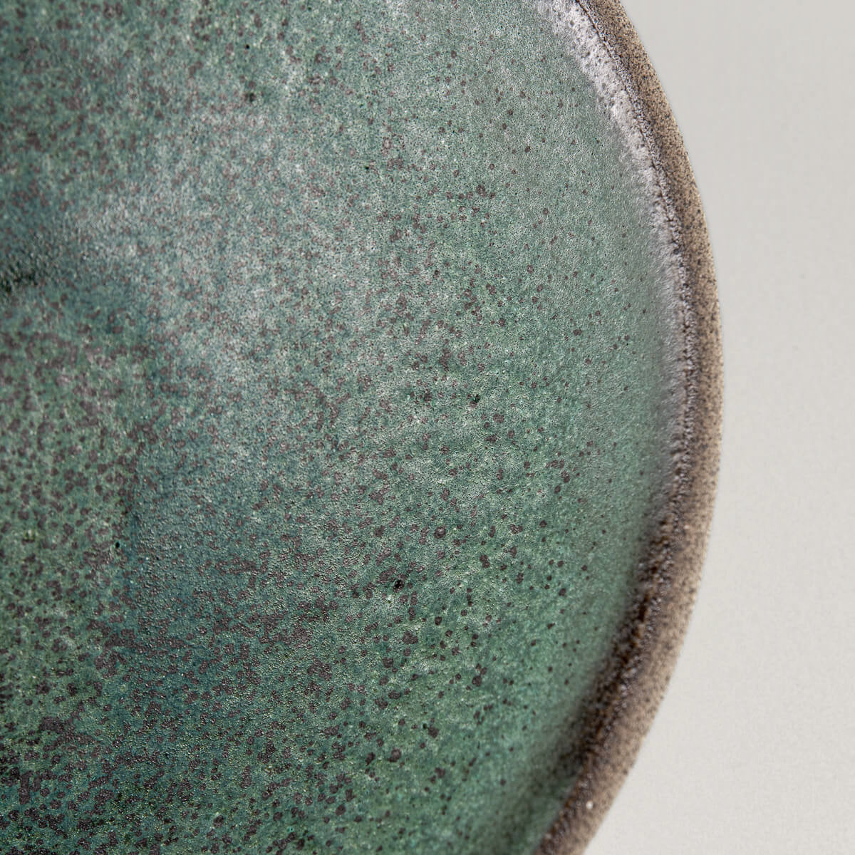 Close-up of green speckled ceramic surface perfect for fine dining and artistic presentation.