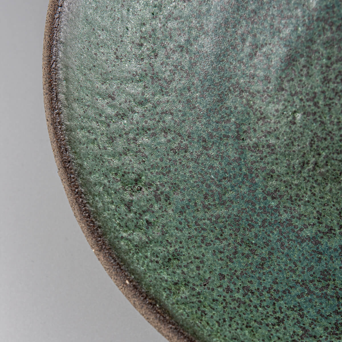 Detail of artisanal dark green glaze on ceramic plate made for collectors and chefs.
