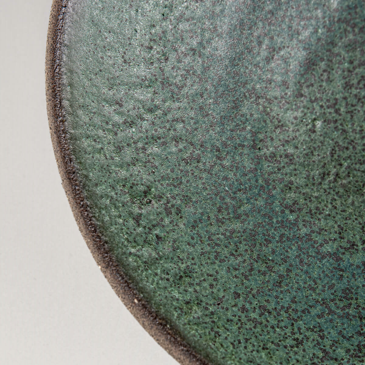 Detail of artisanal dark green glaze on ceramic plate made for collectors and chefs.
