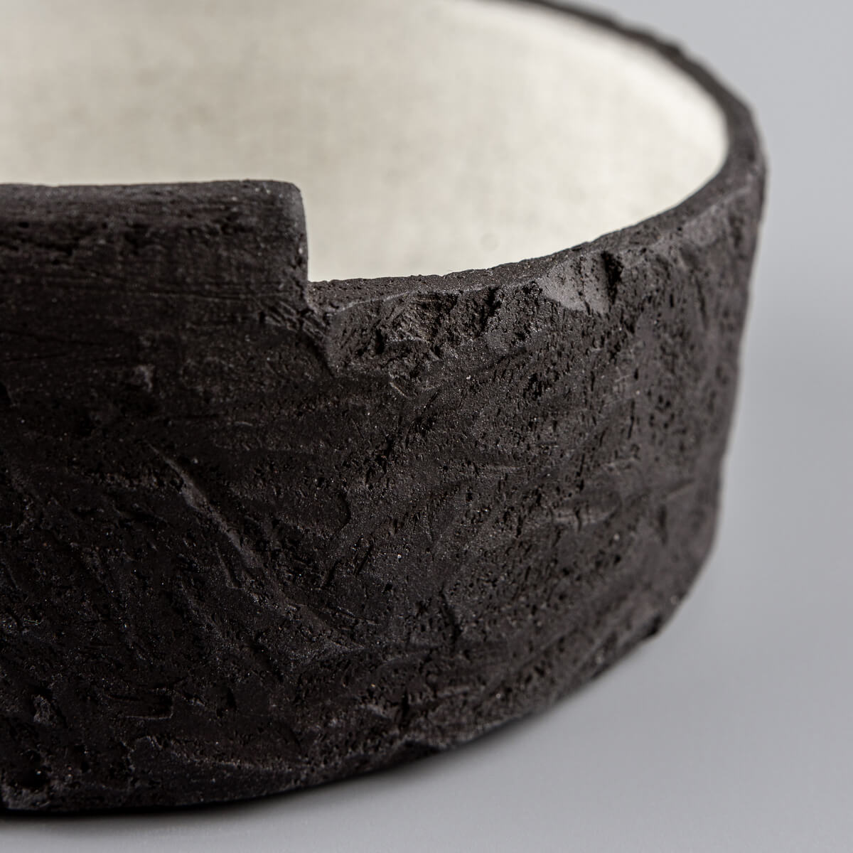 Side angle of unique handmade bowl featuring sculptural black clay and minimalist form.