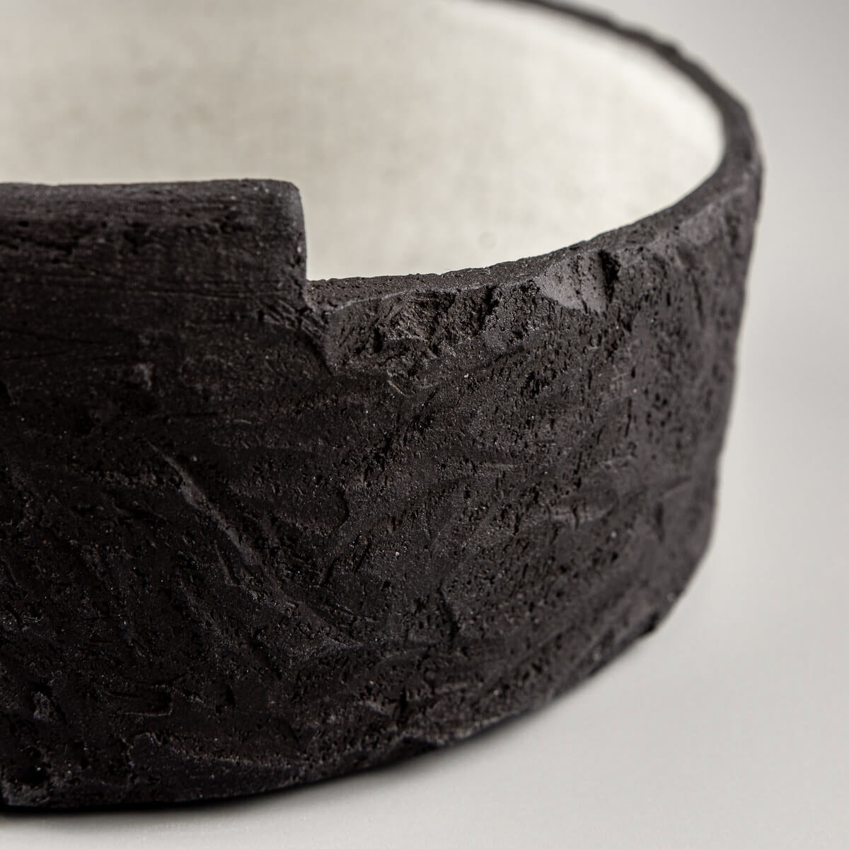 Side angle of unique handmade bowl featuring sculptural black clay and minimalist form.