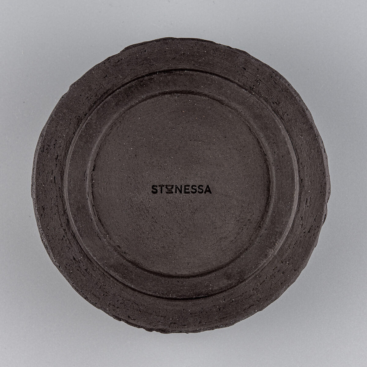 Bottom view of pottery bowl showing artist’s signature and raw ceramic base.