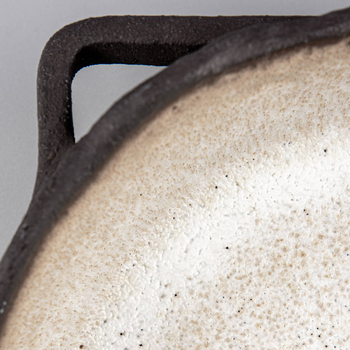 Close-up of handle showing artisanal craftsmanship and raw textured stoneware detail.