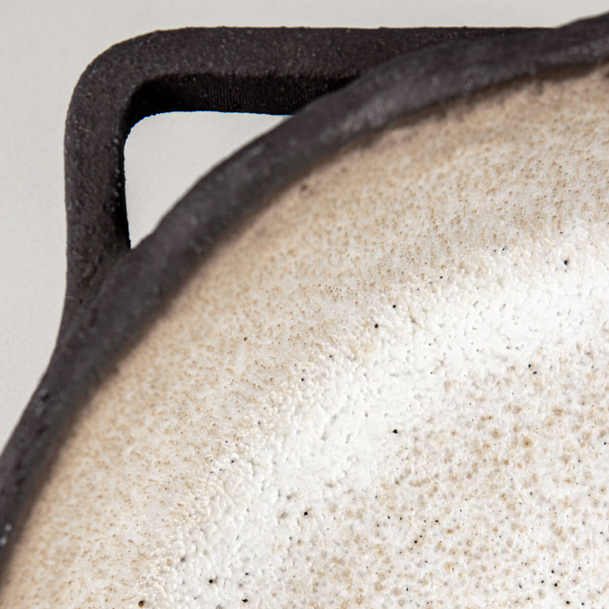 Close-up of handle showing artisanal craftsmanship and raw textured stoneware detail.